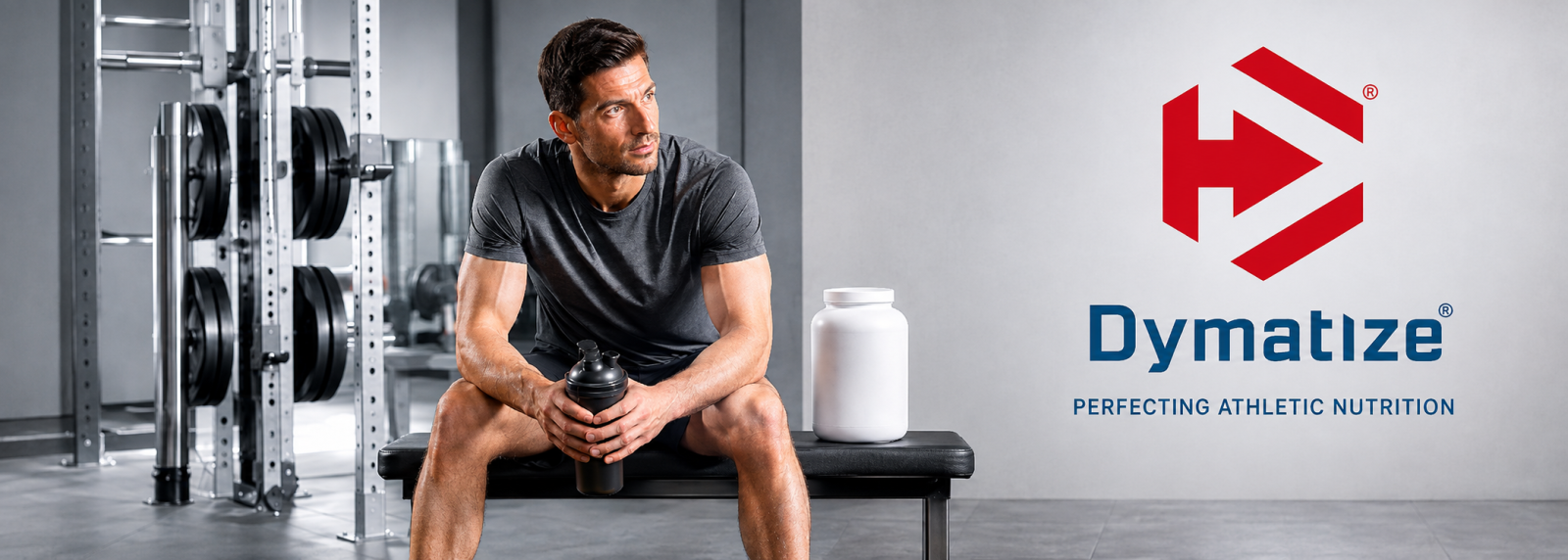 Dymatize Nutrition athlete resting between sets in a modern gym with shaker and protein tub.