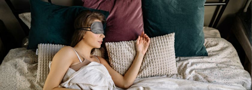 Person resting in bed with a sleep mask for the Sleep Support category.